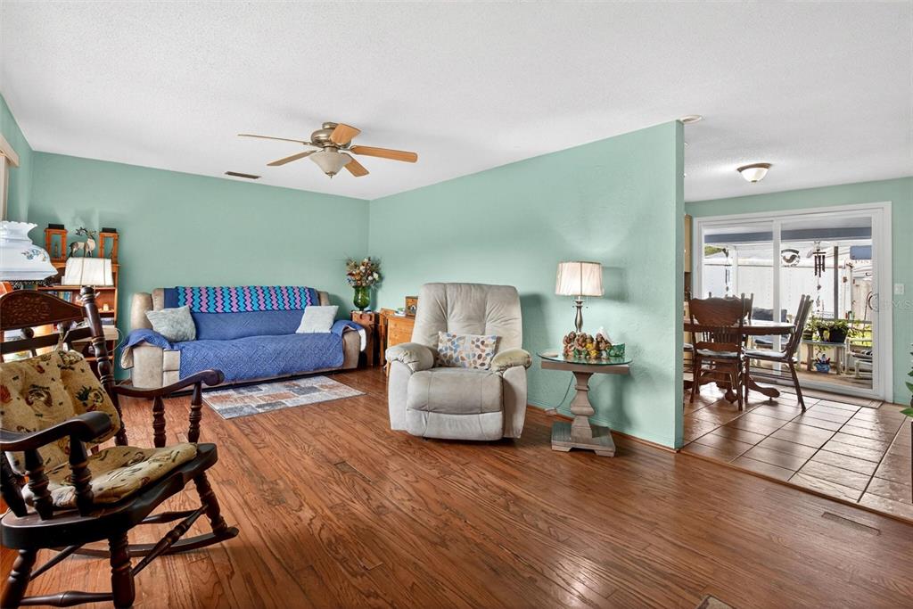 A living room with hardwood floors, a blue sofa, a recliner, and a dining area — 201 POINCIANA AVENUE, PORT ORANGE, FL