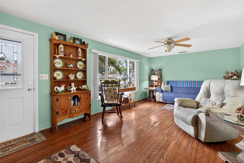 A living room features light green walls, hardwood floors, a wooden hutch, and a ceiling fan — 201 POINCIANA AVENUE, PORT ORANGE, FL