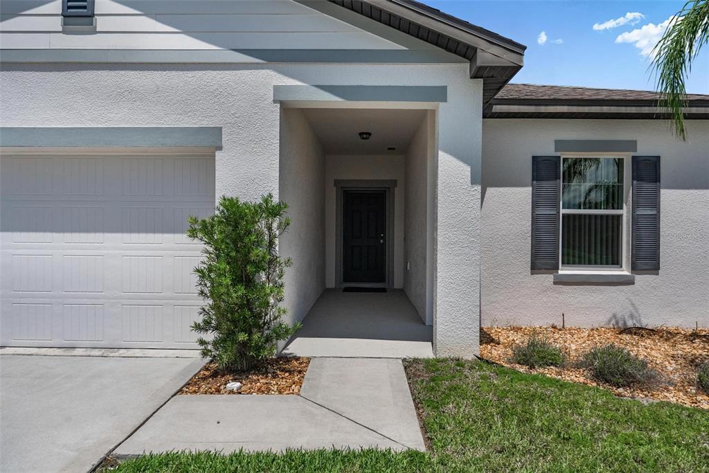The exterior of a house features a white stucco facade, a garage, and a front entrance — 2854 NEVERLAND DRIVE, NEW SMYRNA BEACH, FL