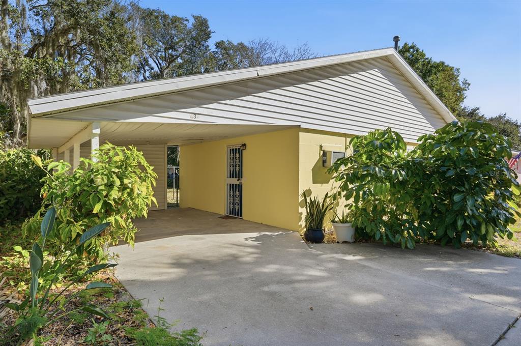 A yellow house exterior features a concrete driveway and a covered carport area — 437 LOCKHART STREET, DAYTONA BEACH, FL