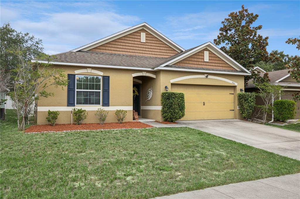 A single-story suburban house with a tan stucco exterior, brown shingle roof, and attached garage — 2541 MARTINS RUN, TAVARES, FL