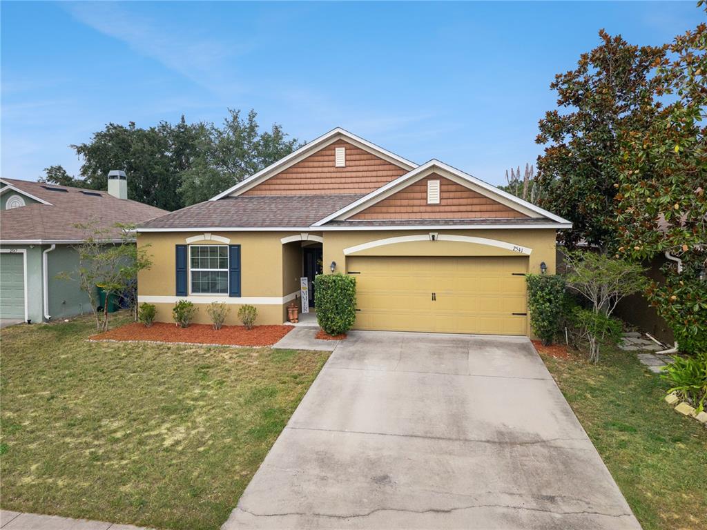 A single-story house with a tan stucco exterior, brown shingle roof, and a concrete driveway — 2541 MARTINS RUN, TAVARES, FL