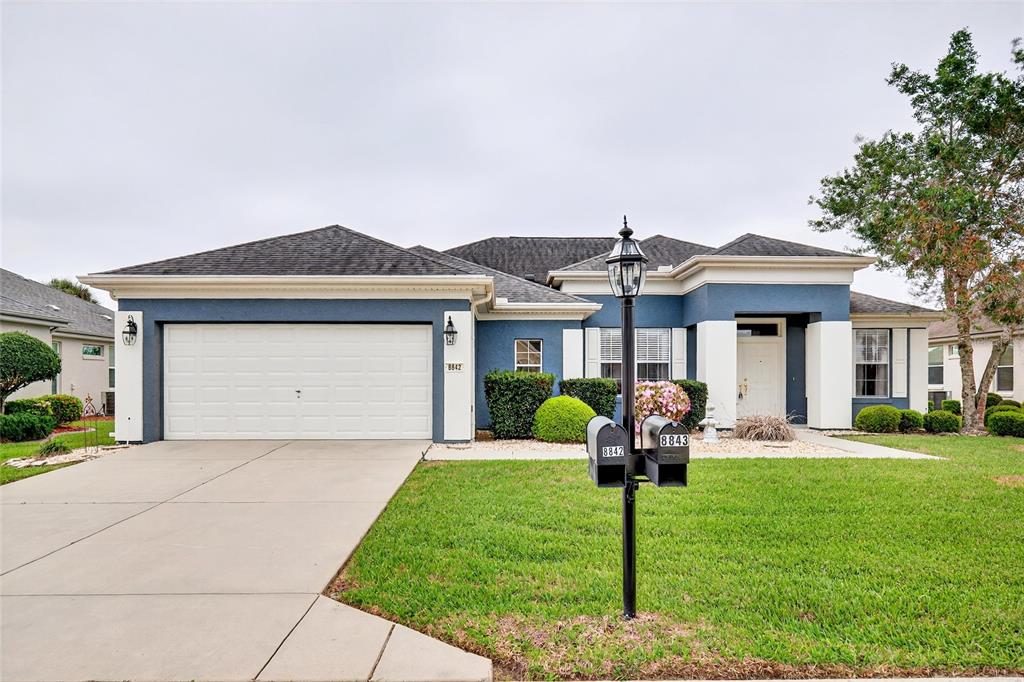 A blue and white single-story house with a two-car garage and a front lawn — 8842 SE 118TH LANE, SUMMERFIELD, FL