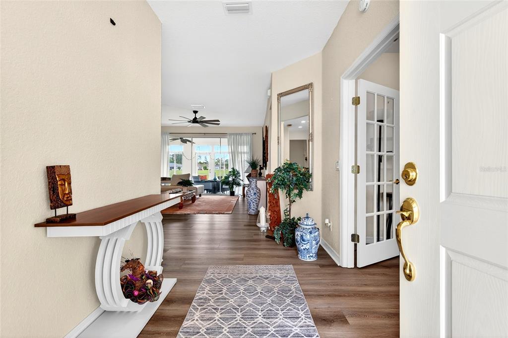 A view from an open front door into a home entryway with wood-look flooring — 8842 SE 118TH LANE, SUMMERFIELD, FL