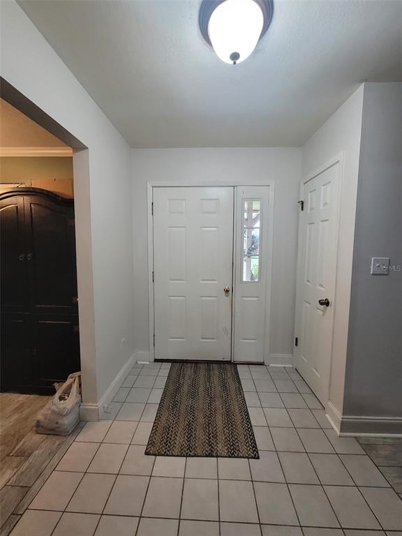 An entryway features a white front door with a sidelight, tiled flooring, and a rug — 617 SAILBOAT DRIVE, NICEVILLE, FL