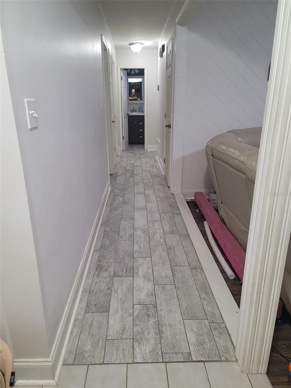A hallway features gray wood-look tile flooring and white walls leading to a bathroom — 617 SAILBOAT DRIVE, NICEVILLE, FL