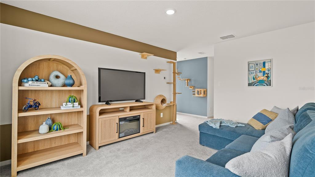 A living room features a blue sectional sofa, a television console, and a cat wall — 587 ARTEMIS STREET, LAKE WALES, FL