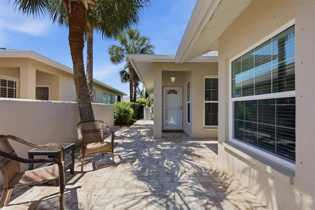A paved patio area features wicker chairs, a palm tree, and a white entry door — 1777 FOUNTAIN VIEW CIRCLE, VENICE, FL