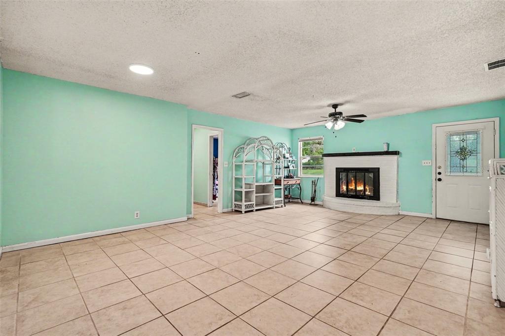A living room with light blue walls, tile flooring, and a white brick fireplace — 7206 ALAFIA DRIVE, RIVERVIEW, FL