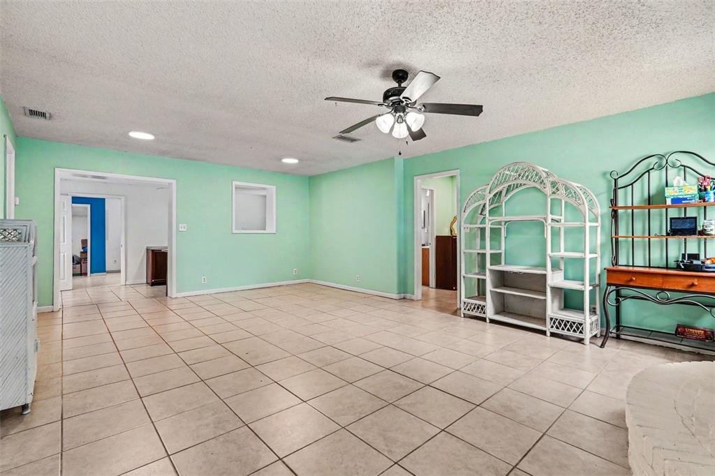 A spacious room with light green walls, tile flooring, a ceiling fan, and white shelving — 7206 ALAFIA DRIVE, RIVERVIEW, FL