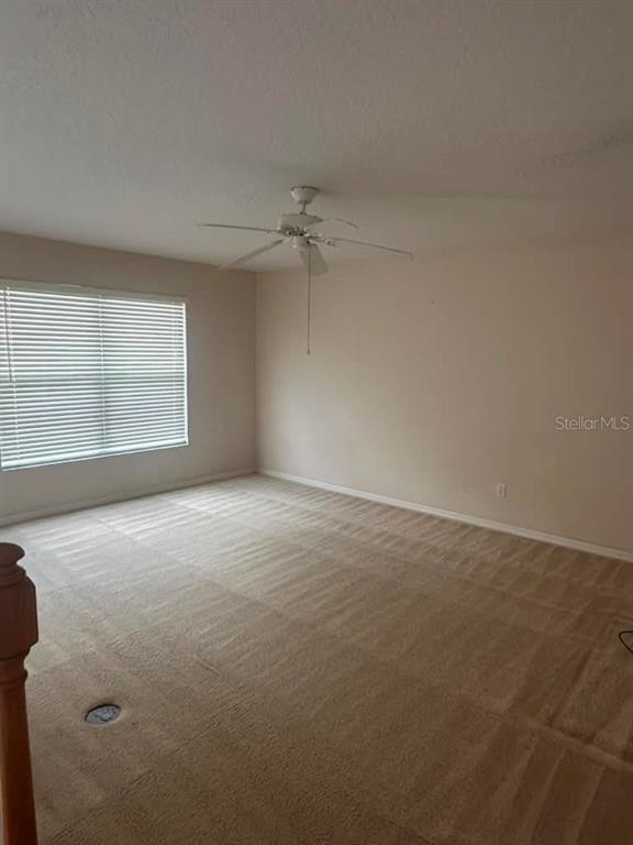 An empty room features beige carpeting, a ceiling fan, and a window with white blinds — 948 TROON CIRCLE, DAVENPORT, FL