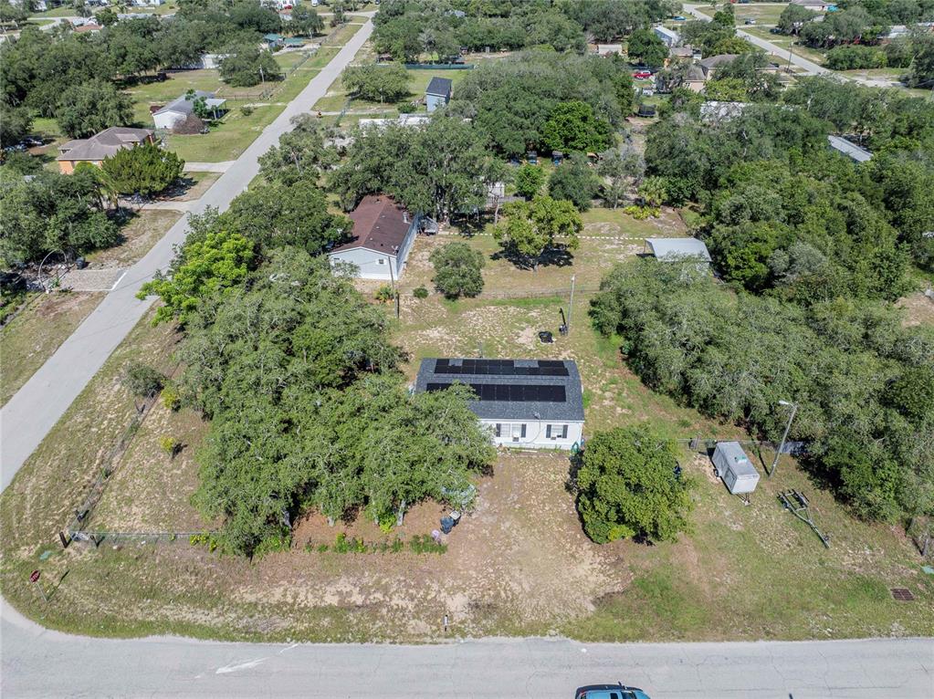 An aerial view shows two houses on a large, tree-filled lot with solar panels — 3825 CARRIAGE DRIVE, LAKE WALES, FL