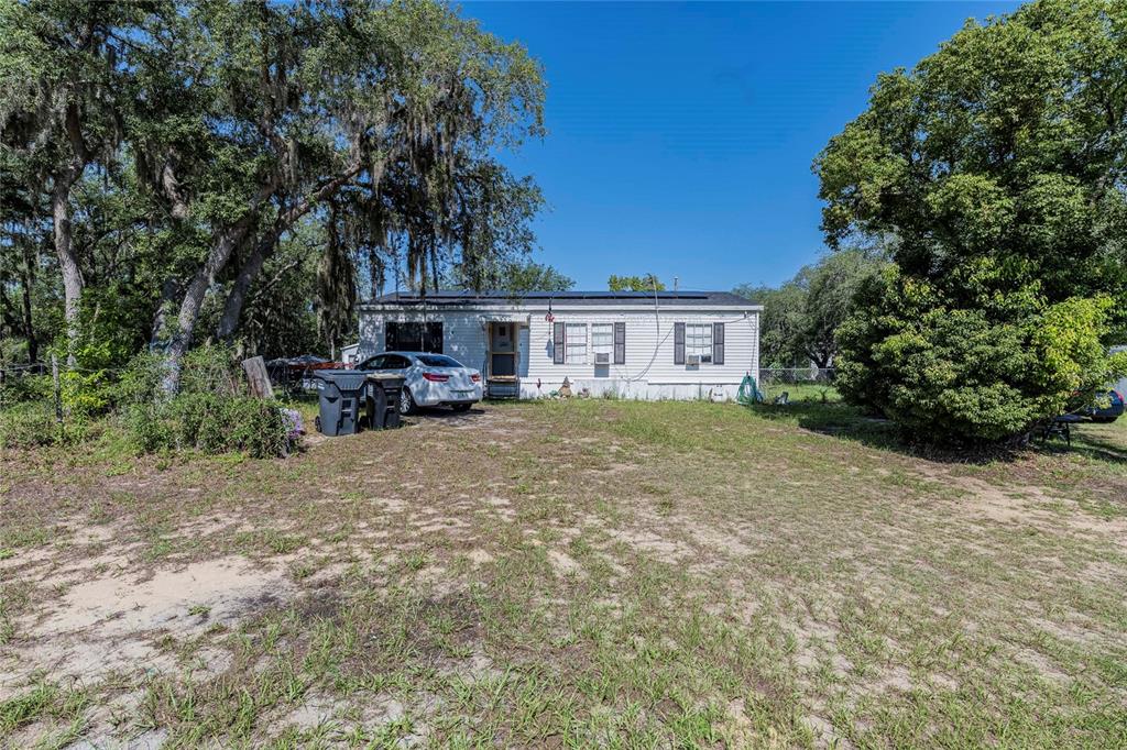 A single-story manufactured home sits on a dirt and grass lot with a parked car — 3825 CARRIAGE DRIVE, LAKE WALES, FL