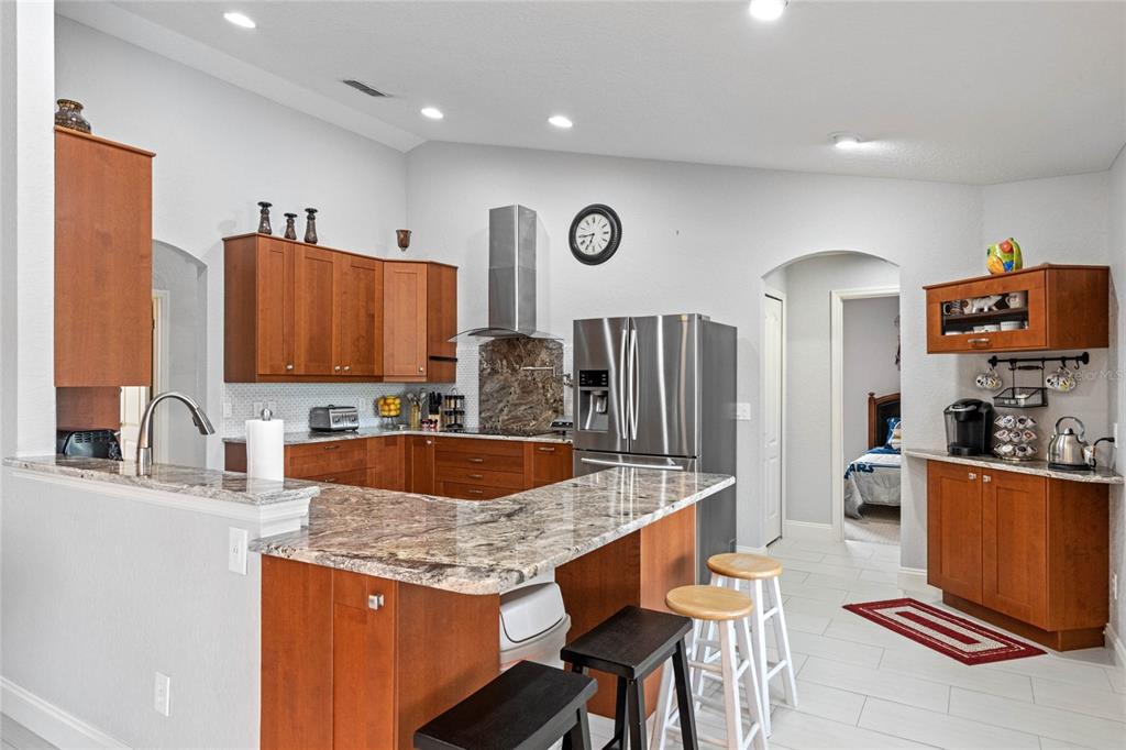 A kitchen features wood cabinets, granite countertops, stainless steel appliances, and a breakfast bar — 300 KINGS WAY, DAVENPORT, FL