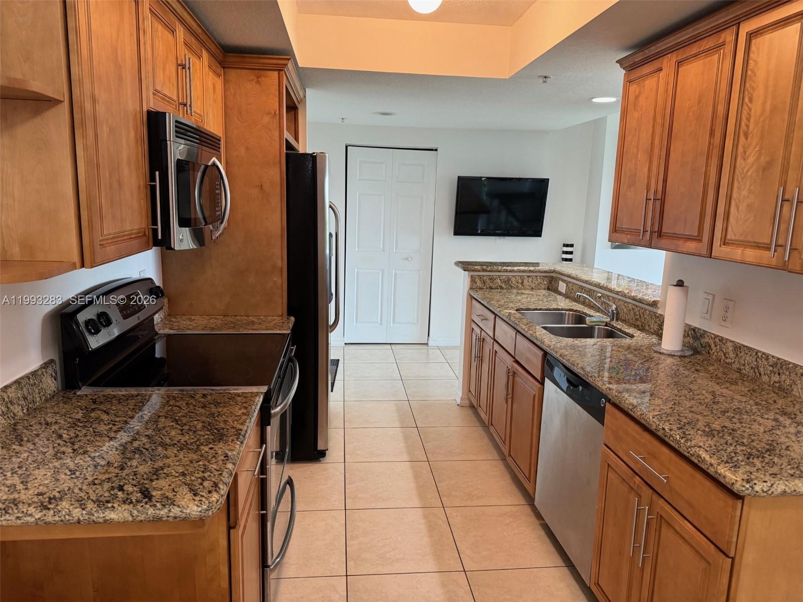 A living room with a blue sofa, glass coffee table, and a balcony with greenery — 3530 SW 22nd St # 706, Miami FL 33145, MIAMI, FL