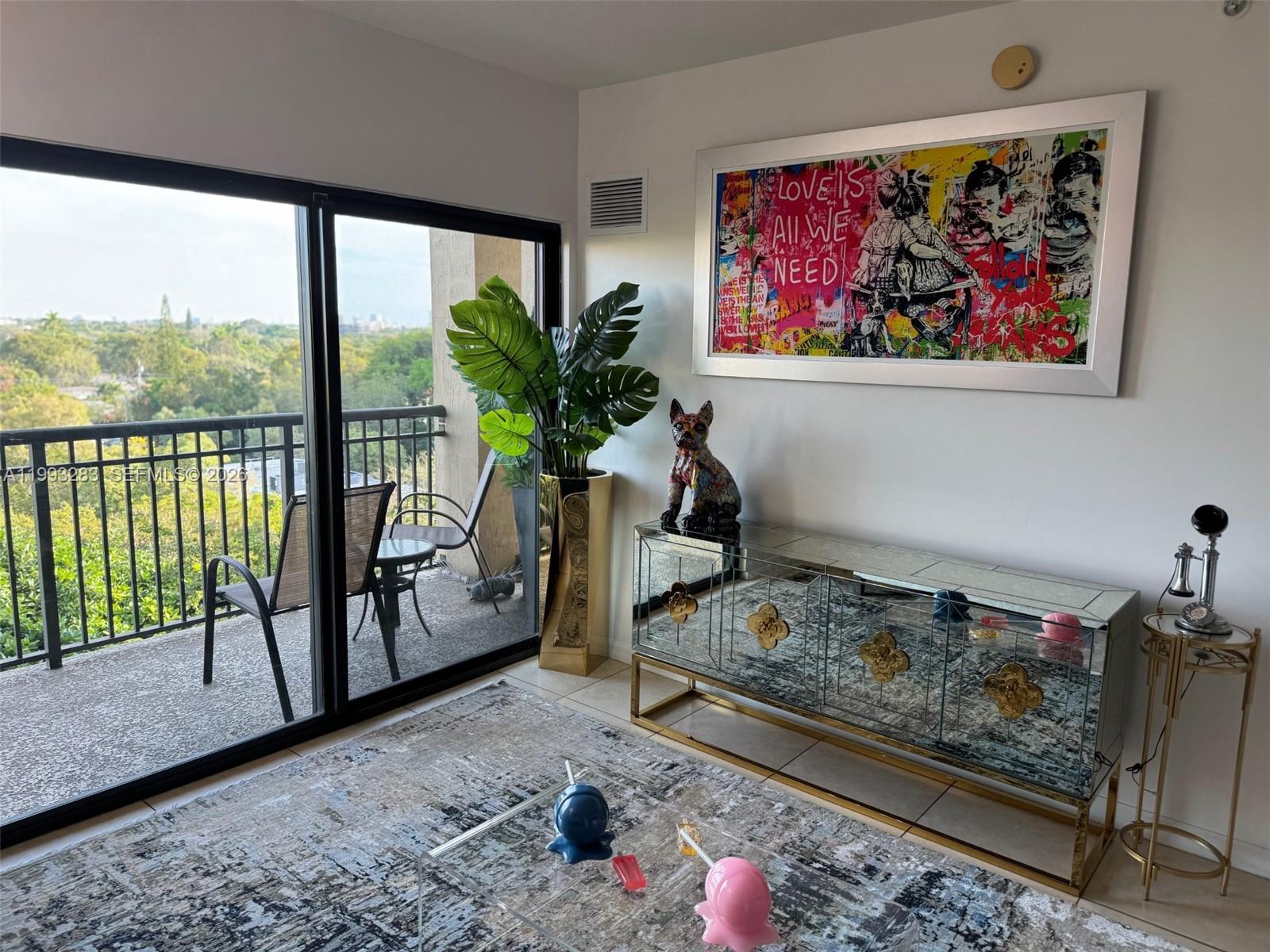 A living room with tile floors, a blue sofa, and a balcony overlooking trees — 3530 SW 22nd St # 706, Miami FL 33145, MIAMI, FL