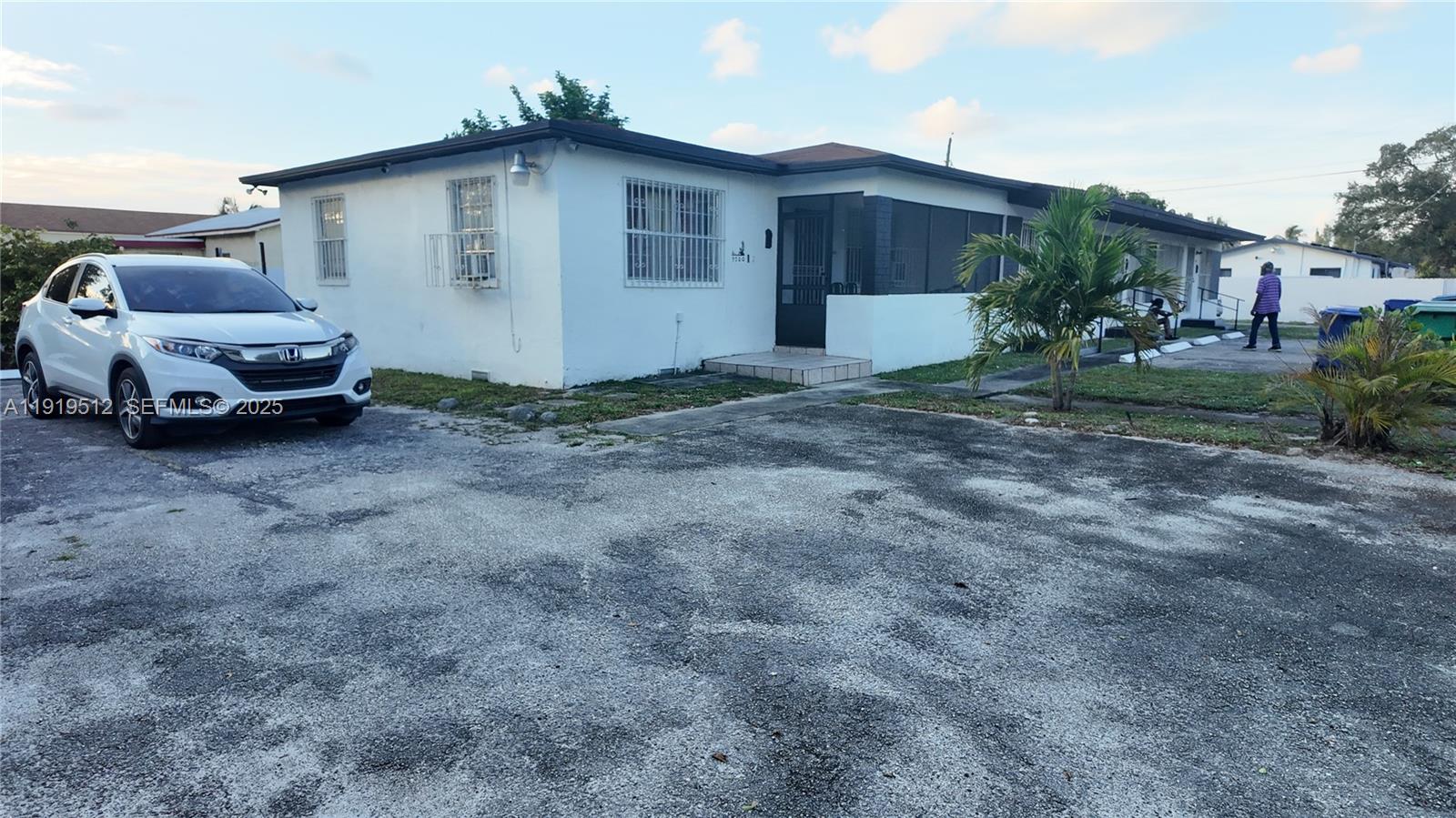 A white single-story house features a screened-in porch and a gravel parking area — 9700 NW 20th Ave, Miami FL 33147, MIAMI, FL