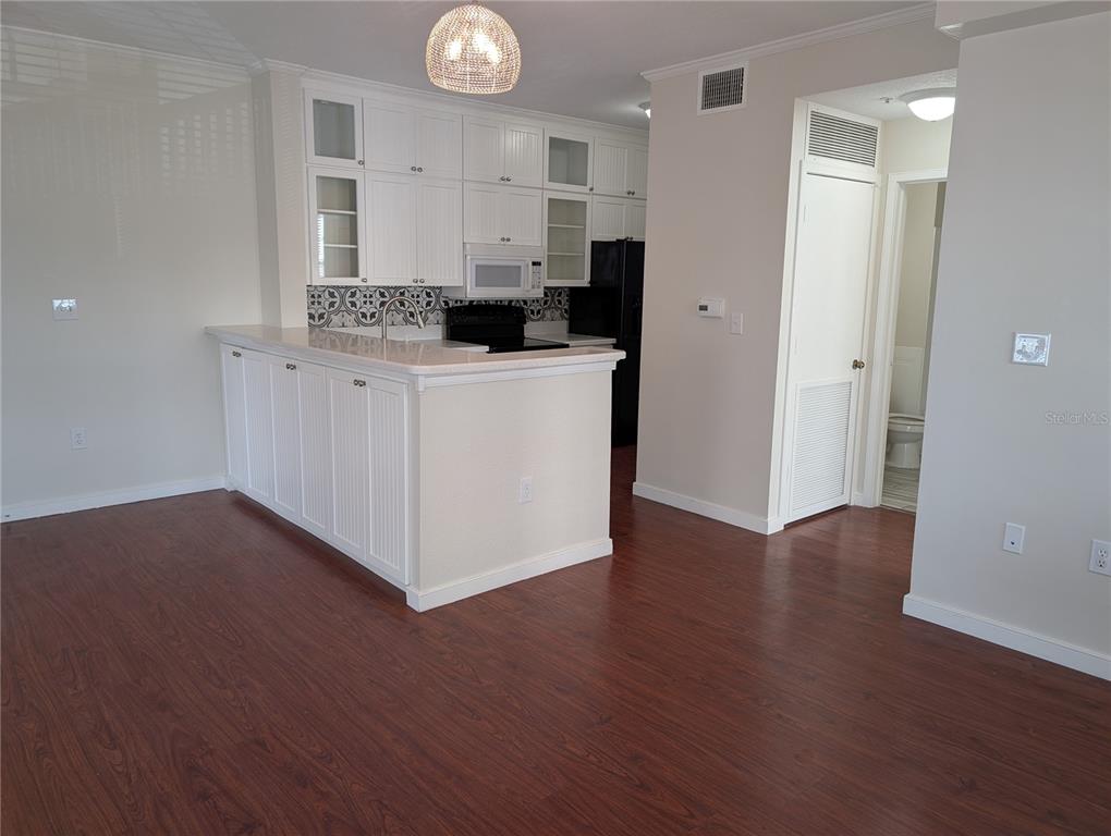 A kitchen with white cabinets, a breakfast bar, and dark wood flooring — 611 CAMPUS STREET UNIT 320, CELEBRATION, FL