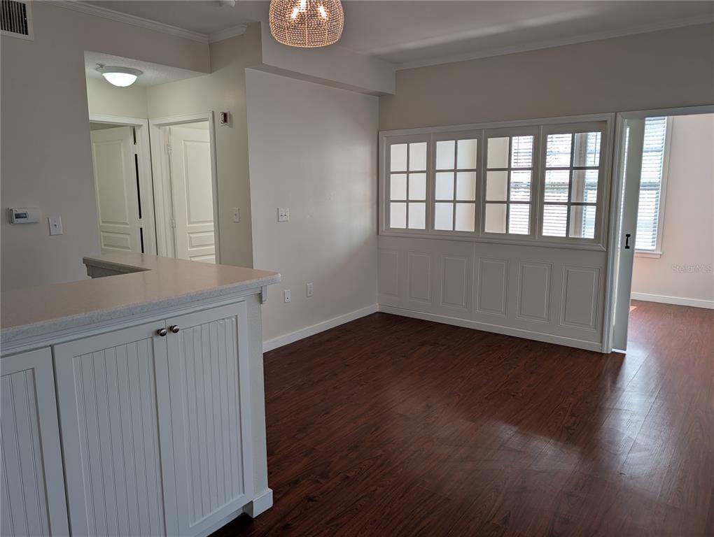 A room with dark wood-look flooring, white cabinetry, and a large interior window partition — 611 CAMPUS STREET UNIT 320, CELEBRATION, FL