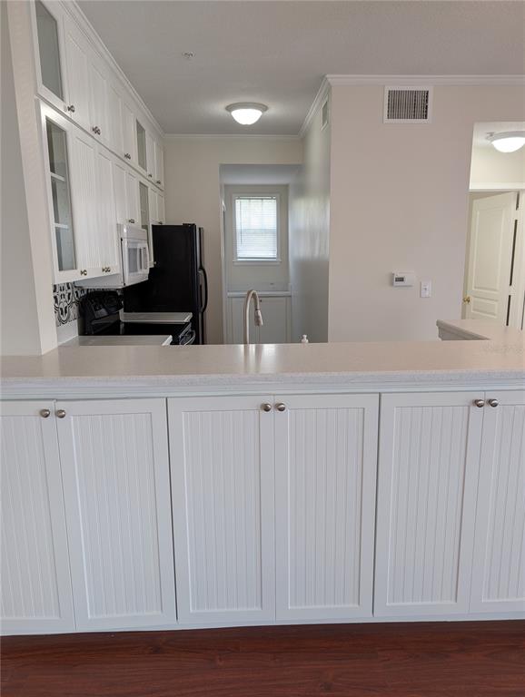 A kitchen features white beadboard cabinetry, a light-colored countertop, and black appliances — 611 CAMPUS STREET UNIT 320, CELEBRATION, FL