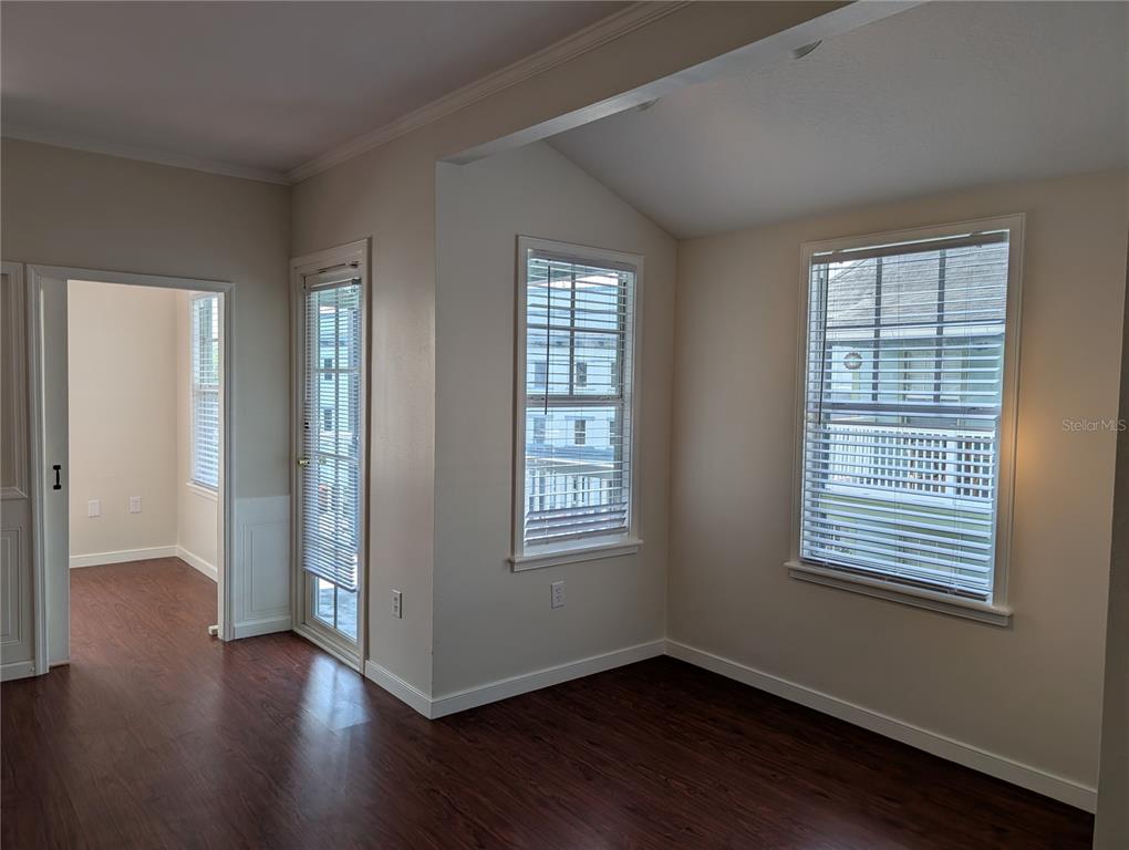 A room with dark wood flooring, two windows, and a glass door leading outside — 611 CAMPUS STREET UNIT 320, CELEBRATION, FL