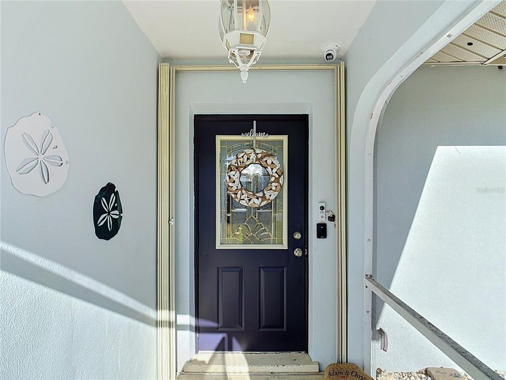 A dark purple front door with a decorative wreath is centered under a porch light — 3637 IDLEWILD STREET, PUNTA GORDA, FL