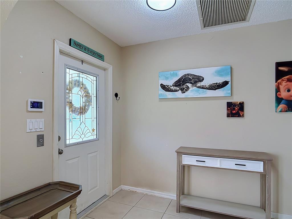 An entryway features a white front door, a console table, and wall art — 3637 IDLEWILD STREET, PUNTA GORDA, FL