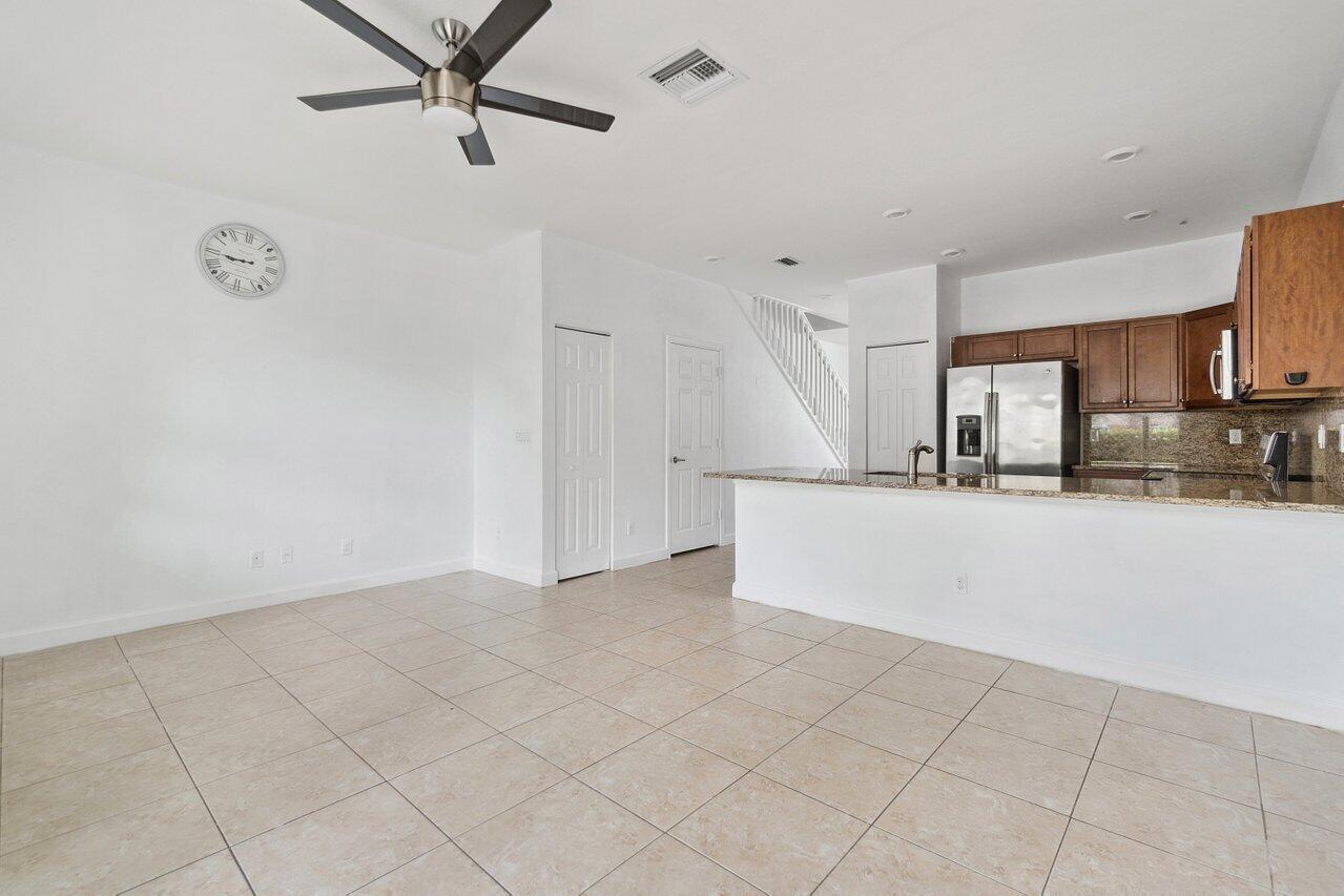 An open-concept living area features tile flooring, a ceiling fan, and an adjacent kitchen — 5288 Ashley River Road, West Palm Beach FL 33417, WEST PALM BEACH, FL