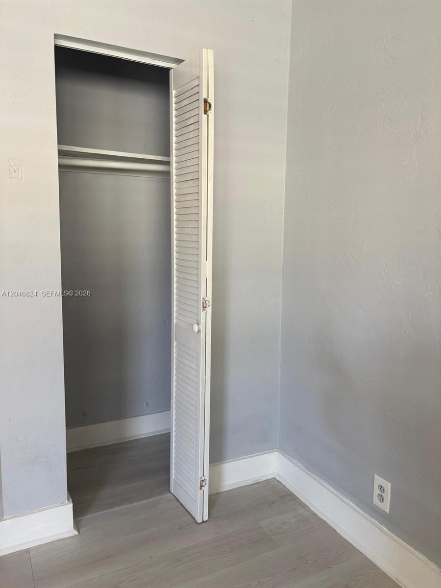 A room features light gray walls, light wood-look flooring, and an open louvered closet door — 1101 NE 5th St # 1, Hallandale Beach FL 33009, HALLANDALE BEACH, FL