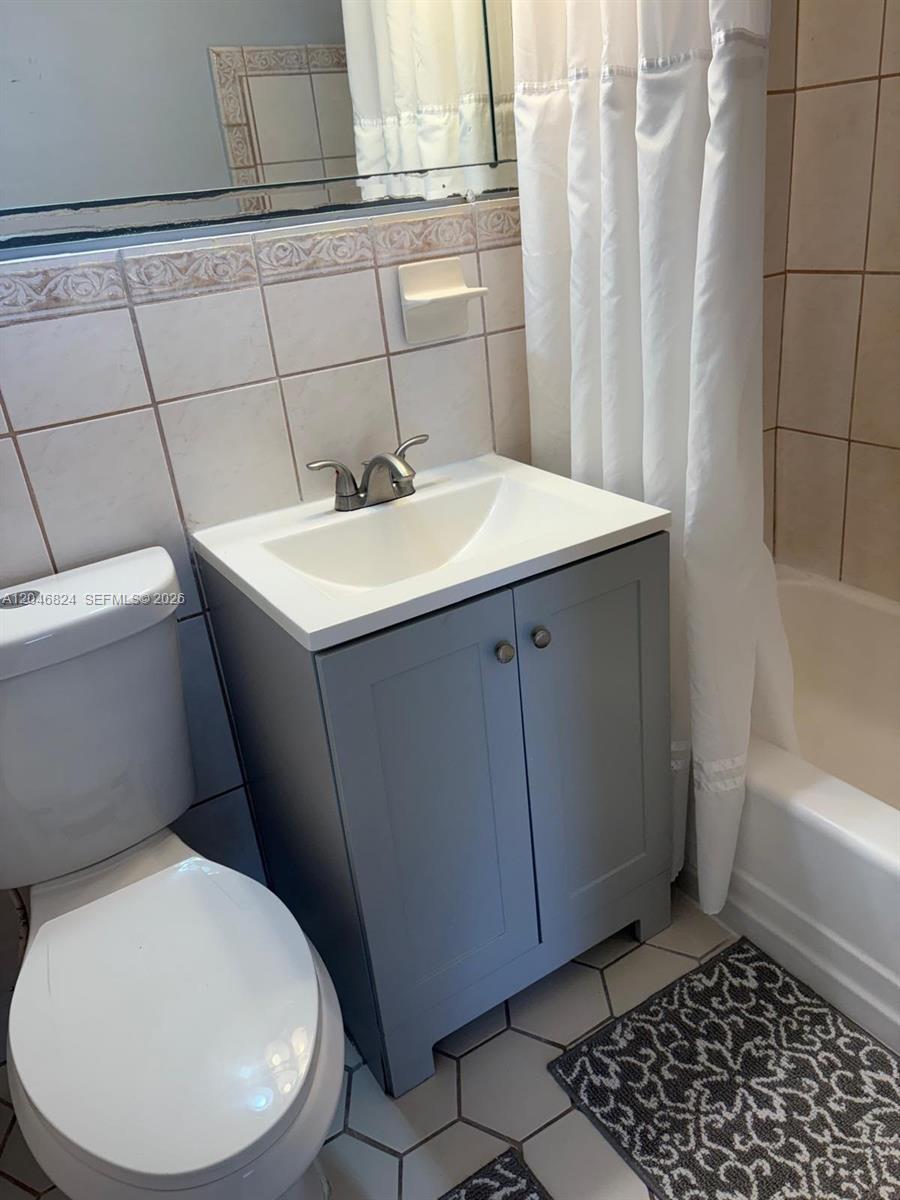 A small bathroom features a gray vanity, white sink, toilet, and a tiled shower area — 1101 NE 5th St # 1, Hallandale Beach FL 33009, HALLANDALE BEACH, FL