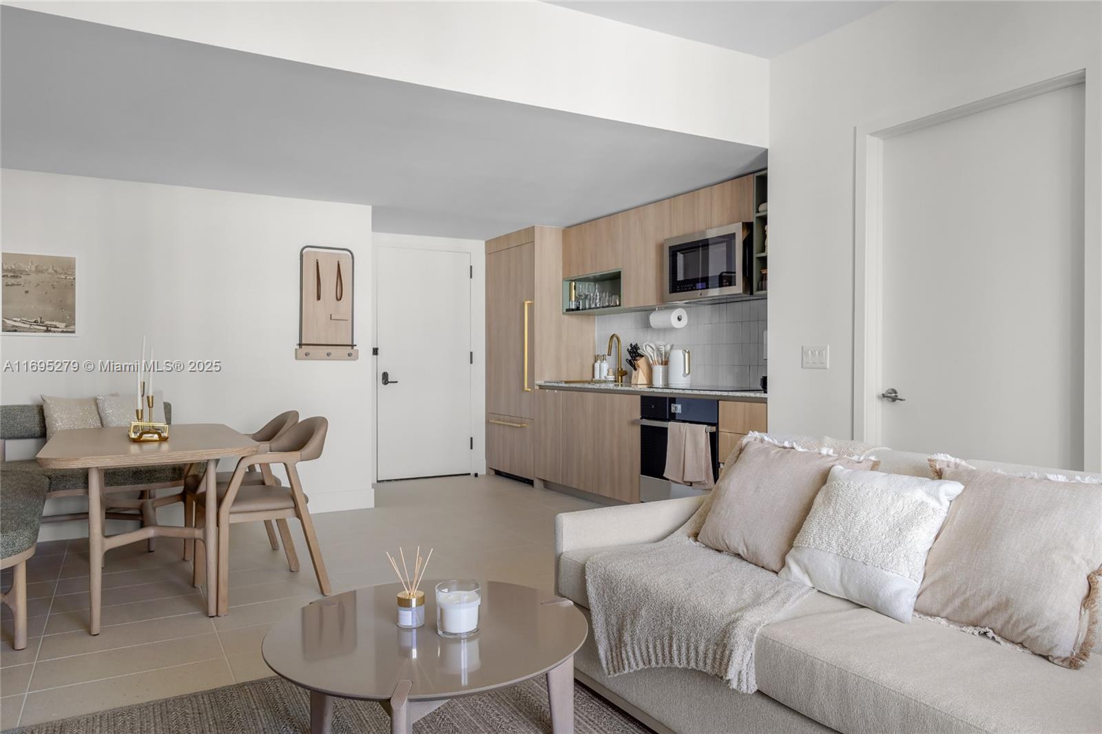 A modern studio apartment features a kitchen with light wood cabinets, a dining area, and sofa — 159 NE 6TH ST # 3209, Miami FL 33132, MIAMI, FL
