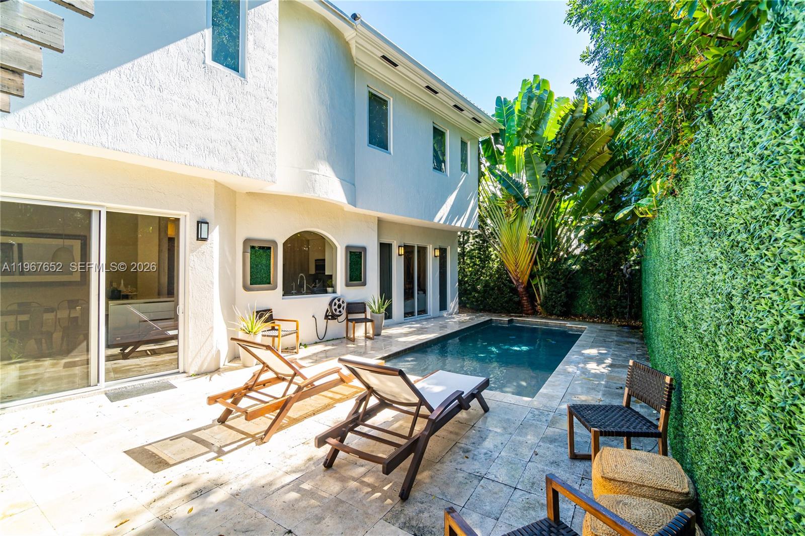 A backyard patio features a swimming pool, lounge chairs, and a tall artificial hedge wall — 2752 Brickell Ct, Miami FL 33129, MIAMI, FL