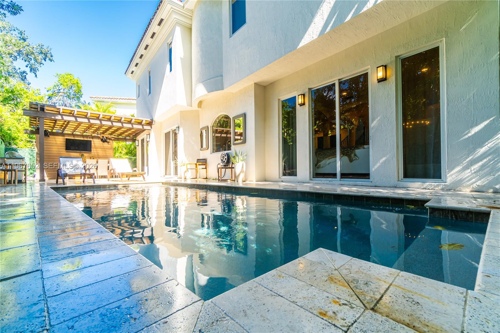 A swimming pool sits in front of a white two-story house with a wooden pergola — 2752 Brickell Ct, Miami FL 33129, MIAMI, FL
