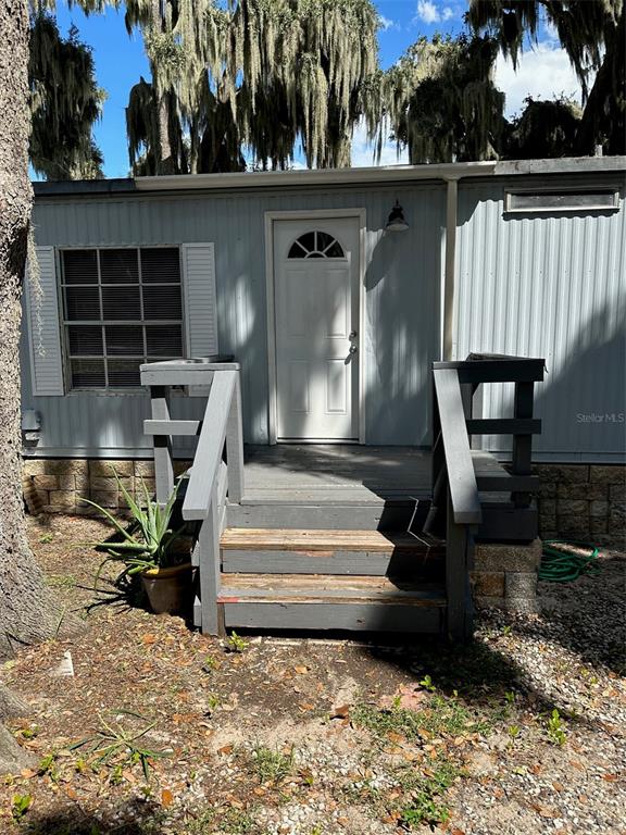 The exterior of a light blue mobile home features a white door and wooden steps — 17110 LIVE OAK LANE, MONTVERDE, FL