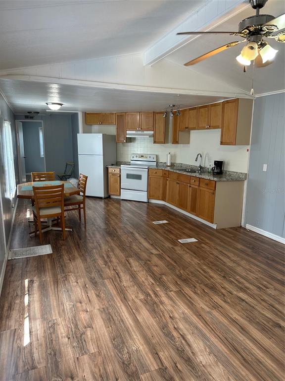 An open-concept kitchen and dining area features wood-look flooring, oak cabinets, and white appliances — 17110 LIVE OAK LANE, MONTVERDE, FL