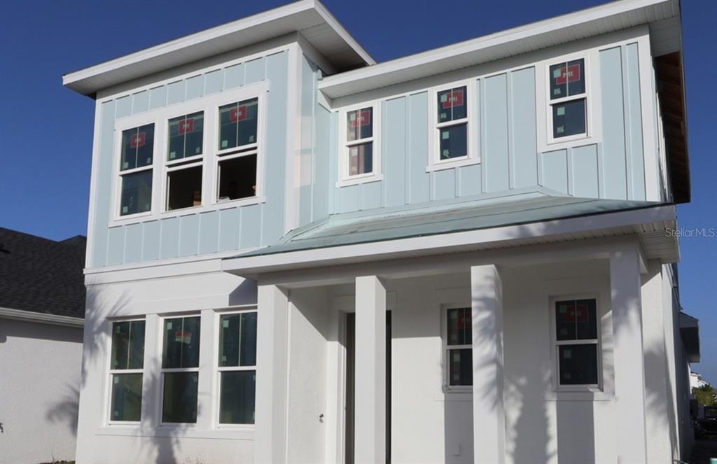 A two-story house exterior features white stucco, light blue vertical siding, and a covered porch — 1590 MERRYTHOUGHT LANE, SARASOTA, FL
