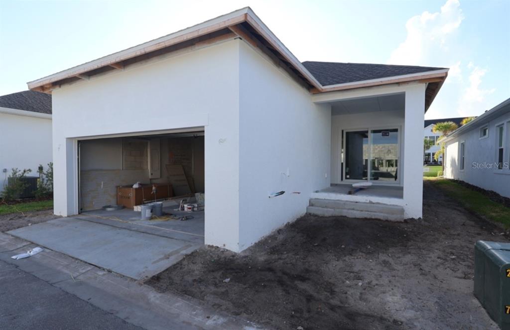 The exterior of a new construction house features a garage and a covered patio entrance — 1590 MERRYTHOUGHT LANE, SARASOTA, FL