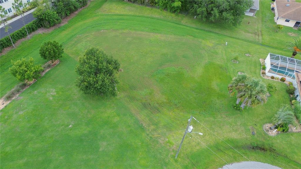 An aerial view shows a large, grassy residential lot with several trees and a utility pole — 481 GUYANA STREET, PUNTA GORDA, FL