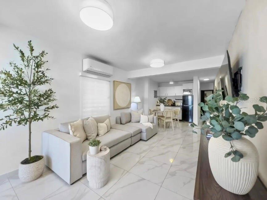 A bright living room features white tile floors, a sectional sofa, and an open kitchen — 310 CALLE TAPIA, SANTURCE, PR