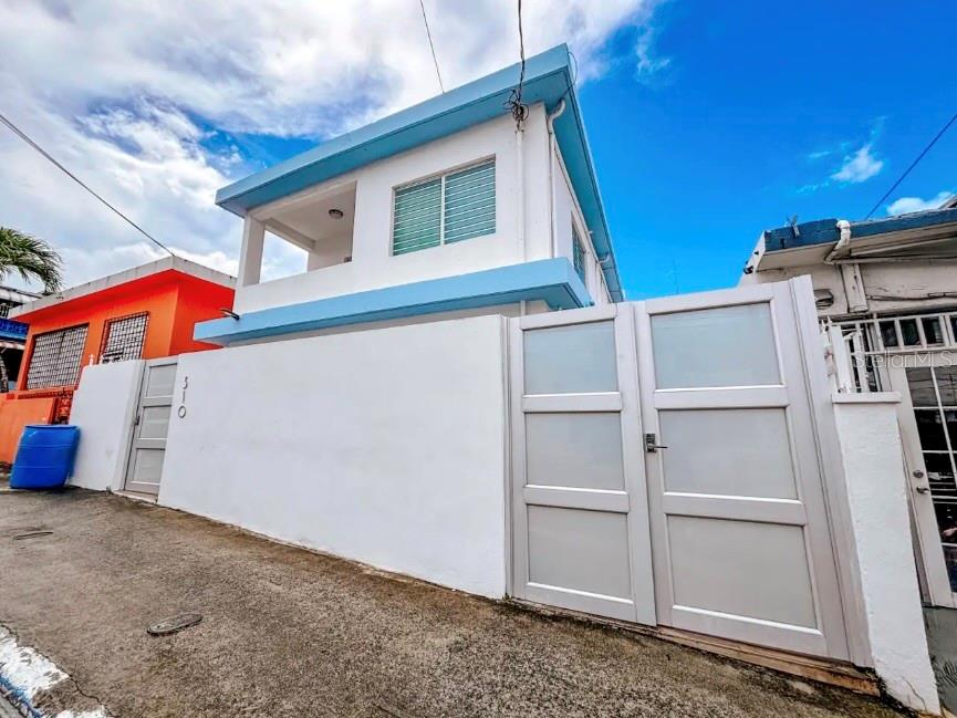 A two-story white house with blue trim and a large white gate on a street — 310 CALLE TAPIA, SANTURCE, PR