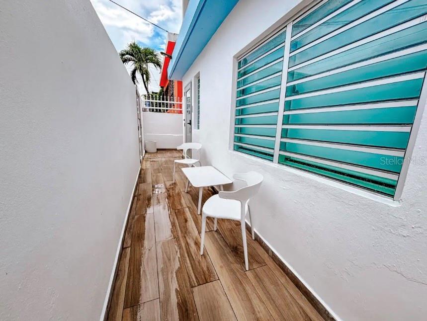A narrow outdoor patio features wood-look tile flooring, white walls, and a small table with chairs — 310 CALLE TAPIA, SANTURCE, PR