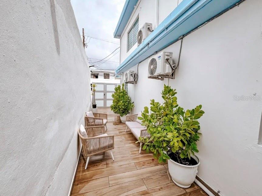 A narrow outdoor patio features wood-look tile flooring, seating, potted plants, and wall-mounted air conditioners — 310 CALLE TAPIA, SANTURCE, PR