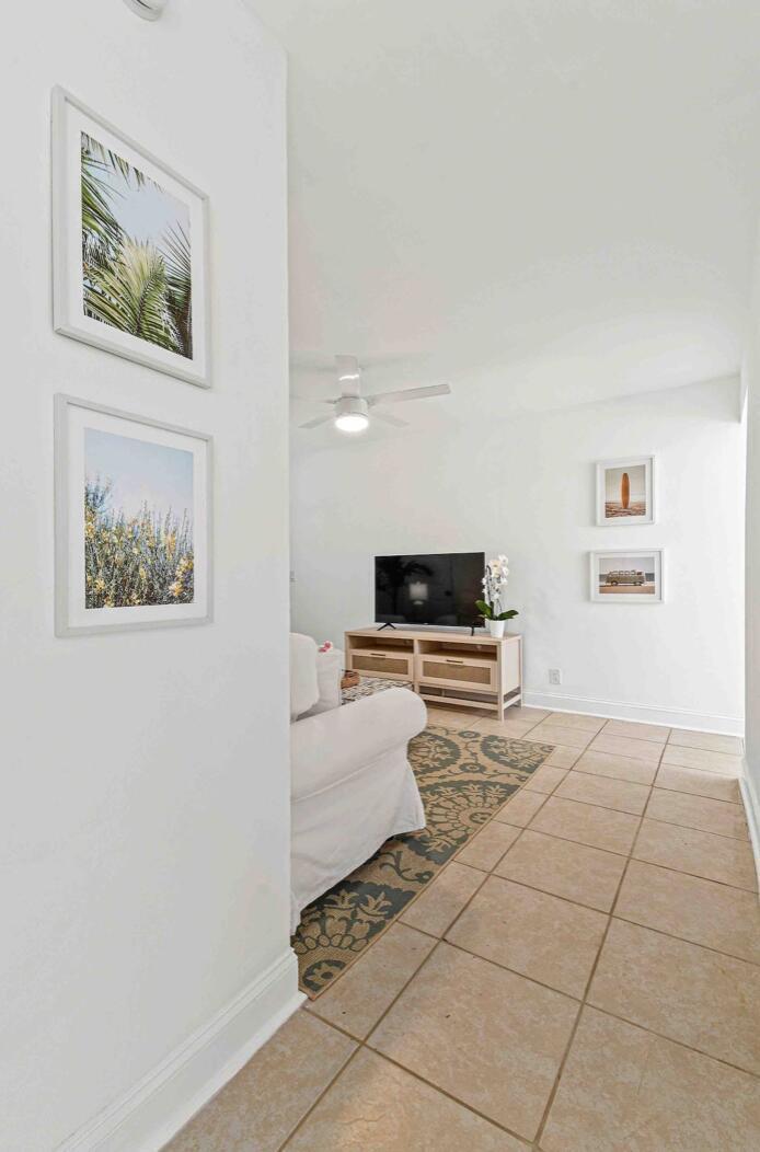 A living room features tiled floors, a white sofa, a television, and framed wall art — 427 Conniston Road # B, West Palm Beach FL 33405, WEST PALM BEACH, FL