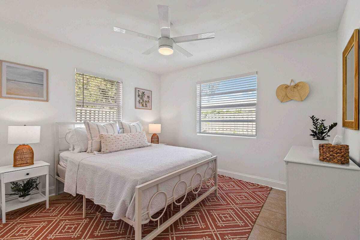 A bedroom features a white metal bed frame, a patterned rug, and two windows — 427 Conniston Road # B, West Palm Beach FL 33405, WEST PALM BEACH, FL