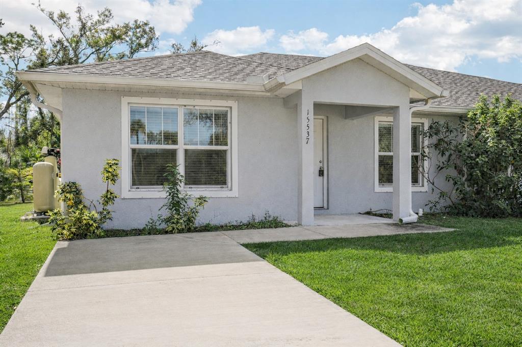 A single-story house with a light gray stucco exterior, a concrete driveway, and a covered entryway — 15537 BUICK AVENUE, PORT CHARLOTTE, FL
