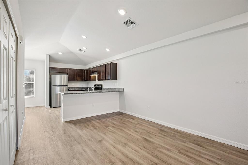 An open-concept kitchen with dark wood cabinets and a breakfast bar overlooks a living area — 15537 BUICK AVENUE, PORT CHARLOTTE, FL