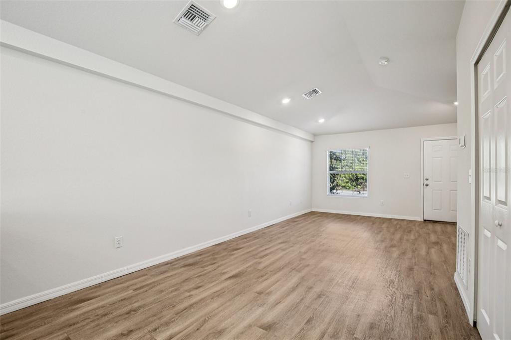 An empty room with white walls, wood-look flooring, recessed lighting, and a single window — 15537 BUICK AVENUE, PORT CHARLOTTE, FL
