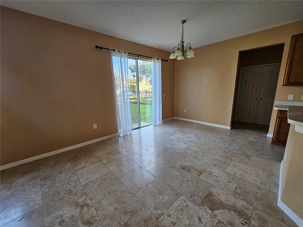 A dining area features tile flooring, a chandelier, and sliding glass doors leading outside — 1881 STRATHMORE CIRCLE, MOUNT DORA, FL