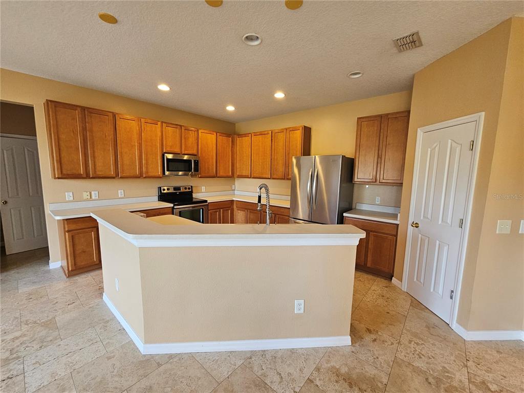 A kitchen features wood cabinets, stainless steel appliances, a breakfast bar, and tile flooring — 1881 STRATHMORE CIRCLE, MOUNT DORA, FL