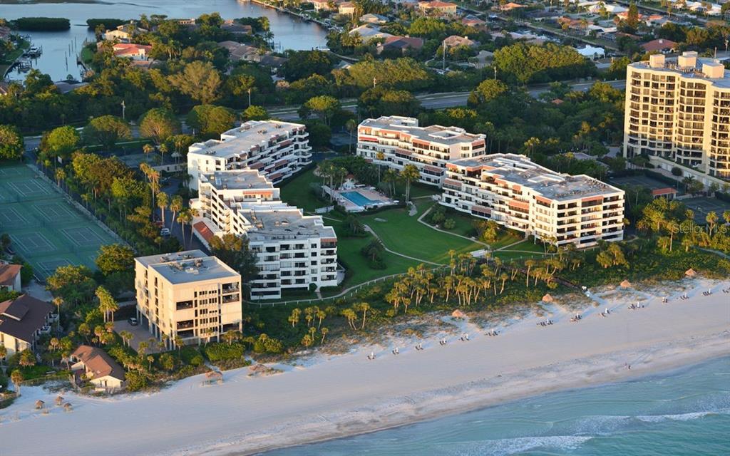 An aerial view of beachfront condominium buildings with a swimming pool and tennis courts — 1485 GULF OF MEXICO DRIVE UNIT 109, LONGBOAT KEY, FL